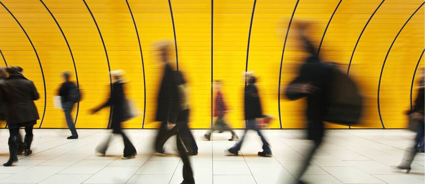 Je ziet mensen voorbij een felle gele wand van rechts naar links lopen.